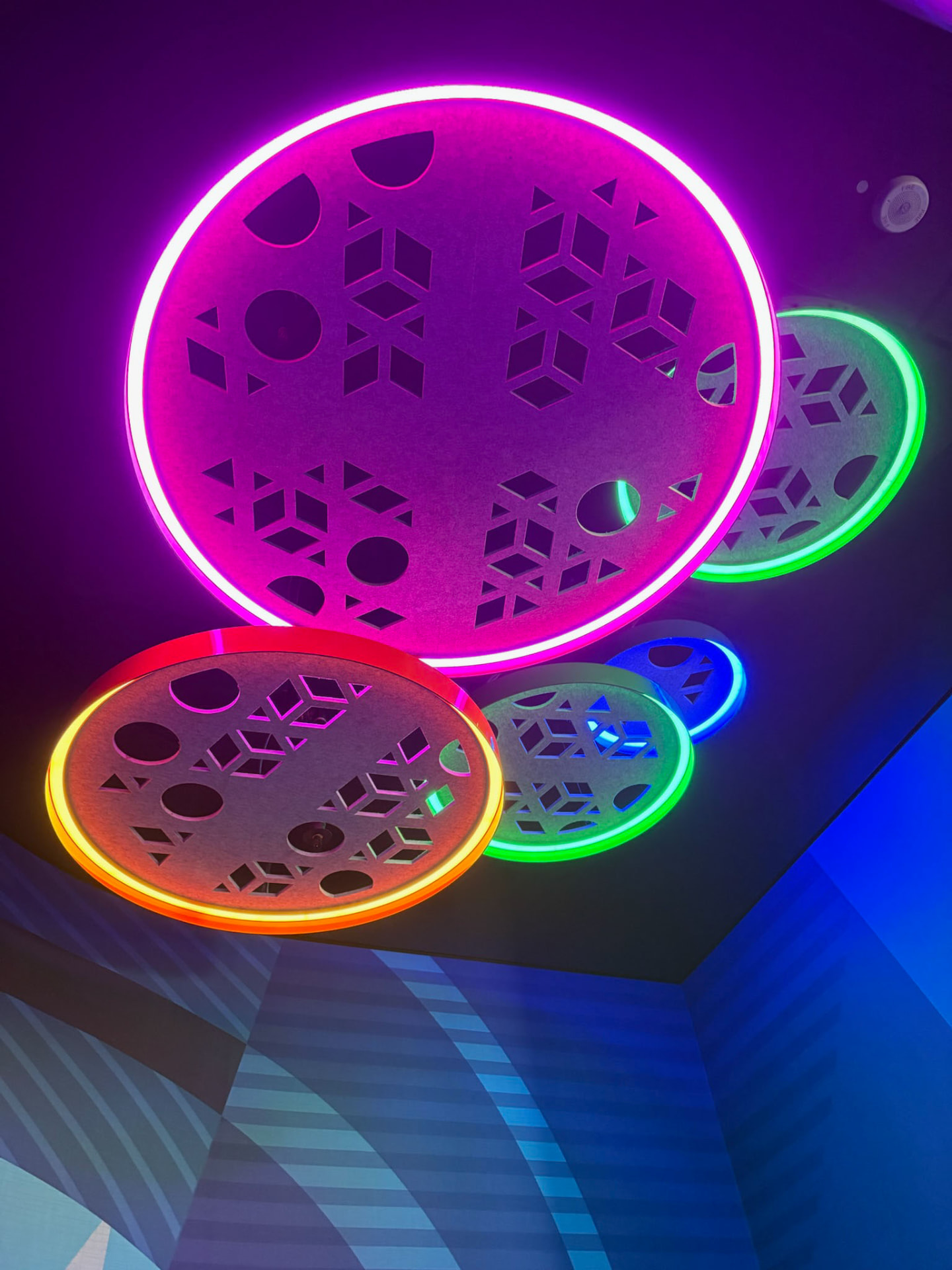 Colorful neon-lit ceiling discs glowing pink, green, and orange